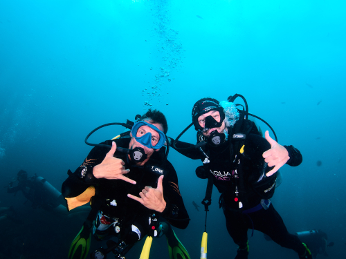 Two divers giving the shaka sign underwater, AquaTao